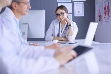 Ciddi bir tıbbi ekip parlak bir ofiste dizüstü bilgisayar kullanıyor.