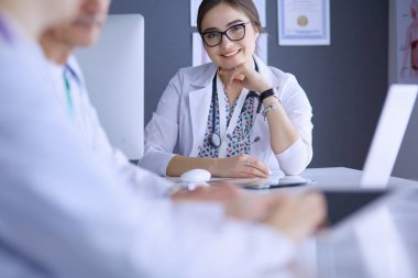 Ciddi bir tıbbi ekip parlak bir ofiste dizüstü bilgisayar kullanıyor.