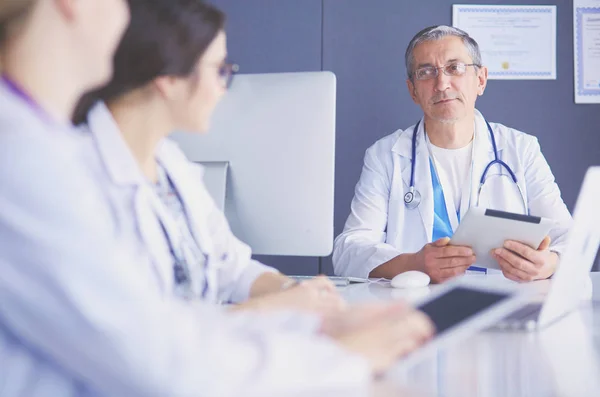 Equipe médica séria usando um laptop em um escritório brilhante — Fotografia de Stock