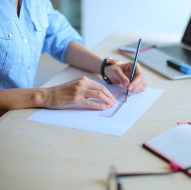 Ofis masasında dizüstü bilgisayarla oturan genç bir kadın. Genç bir kadın. Dizüstü bilgisayar