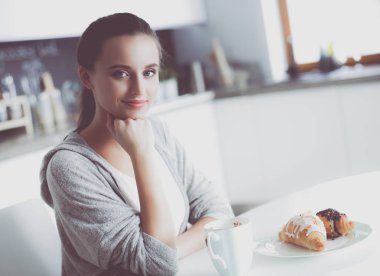 Mutfak masasında tatlı kruvasan ile çay içme kadın.