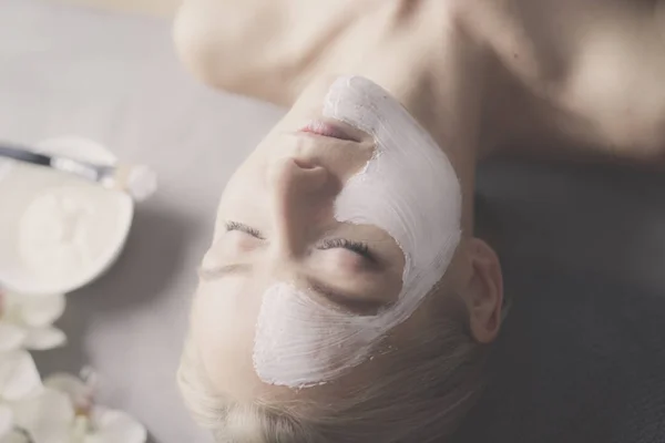 Ansiktsmask. Vacker ung flicka på spa, cosmetician kvinna tillämpa ansiktsmask. — Stockfoto