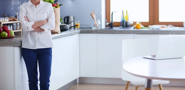 Retrato de jovem de pé com os braços cruzados contra o fundo da cozinha. Mulher na cozinha . — Fotografia de Stock