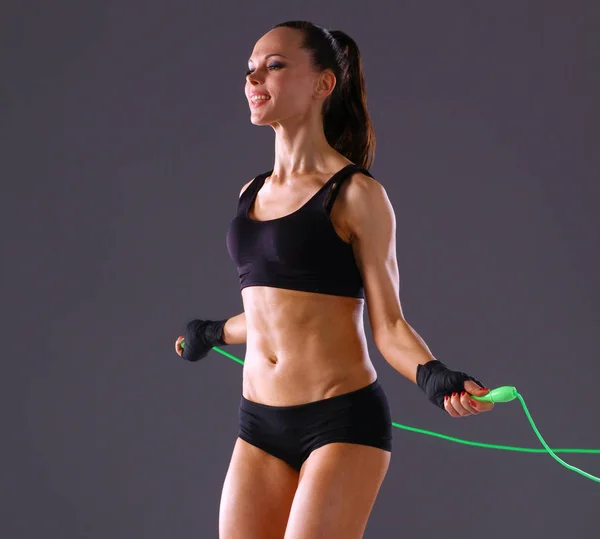 Muskulöse junge Frau, die auf grauem Hintergrund steht. muskulöse junge Frau. schönes Mädchen beim Seilspringen — Stockfoto