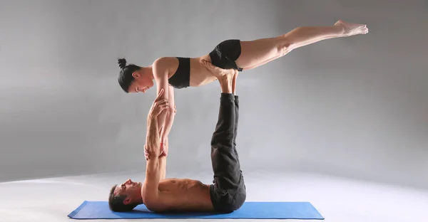 Giovane coppia praticare acro yoga sul tappeto in studio insieme. Acroyoga. Un paio di yoga. Partner yoga . — Foto Stock