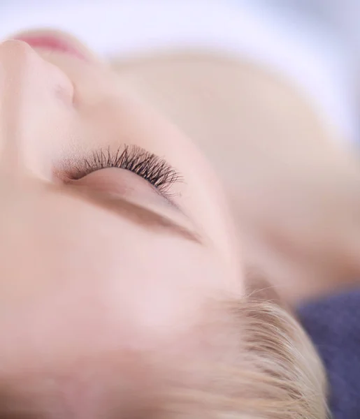 Mujer joven acostada en una mesa de masaje, relajándose con los ojos cerrados. Una mujer. Salón de spa — Foto de Stock