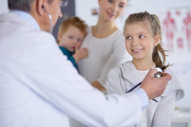 Steteskoplu kız ve doktor kalp atışlarını dinliyor.