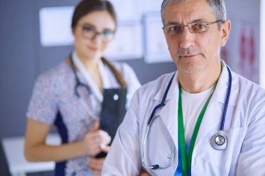 Bir doktor ekibi, kadın ve erkek, ofiste bekliyorlar.