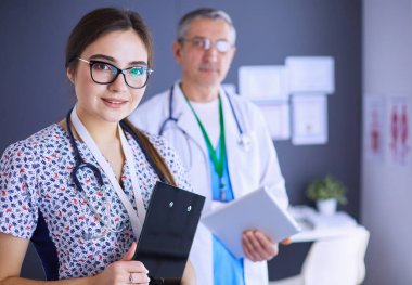 Bir doktor ekibi, kadın ve erkek, ofiste bekliyorlar.