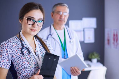 Bir doktor ekibi, kadın ve erkek, ofiste bekliyorlar.