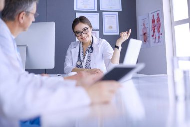 Ciddi bir tıbbi ekip parlak bir ofiste dizüstü bilgisayar kullanıyor.