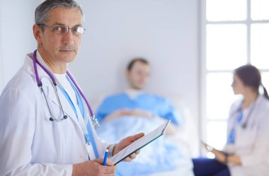 Doktor bir hastanın ve doktorun önünde klasörü tutuyor.