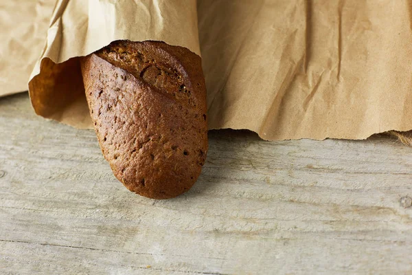 En brödlimpa förpackad i papper på träbord. — Stockfoto