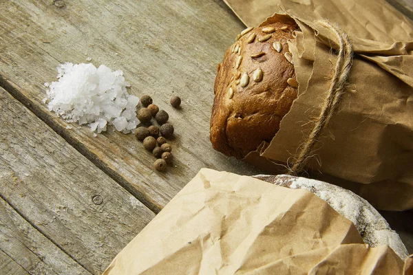 Tahta masanın üzerinde kağıda sarılı bir somun ekmek.. — Stok fotoğraf