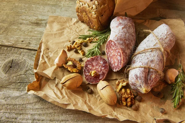 Italienische Salami mit Meersalz, Rosmarin, Knoblauch und Nüssen auf Papier. Rustikaler Stil. Nahaufnahme. — Stockfoto