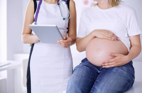 Doctora joven examinando a una mujer embarazada en la clínica. — Foto de Stock