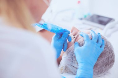 Kaşlar için kalıcı makyaj. Güzellik salonunda kalın kaşlı güzel bir kadın..