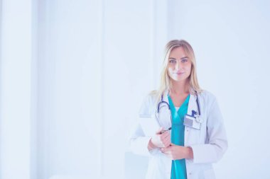 Genç bir kadın doktorun portresi, elinde aipad ile, bir tıp ofisinde.