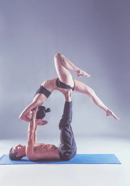 Pareja joven practicando acro yoga en estera en estudio juntos. Acroyoga. Un par de yoga. Socio yoga . — Foto de Stock