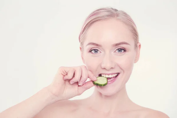 Mooie jongedame met plakjes komkommer op witte achtergrond. — Stockfoto