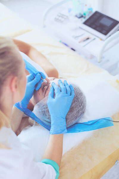 Permanent makeup for eyebrows. Closeup of beautiful woman with thick brows in beauty salon.