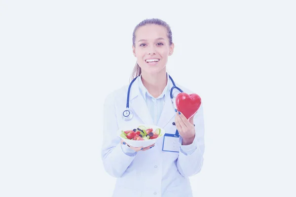 Porträt einer schönen Ärztin, die einen Teller mit frischem Gemüse und rotem Herz in der Hand hält. Ärztinnen. — Stockfoto