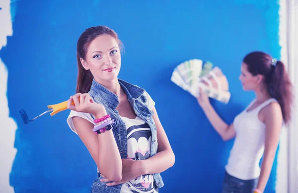 Dos hermosas mujeres jóvenes sosteniendo la paleta de colores, de pie cerca de la pared. Dos mujeres hermosas jóvenes —  Fotos de Stock