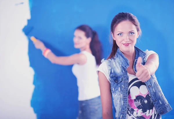 Two Young beautiful women holding color palette , standing near wall. Two Young beautiful women — Stock Photo, Image