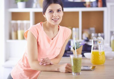 Mutfakta dijital tablet kullanan güzel genç bir kadın..