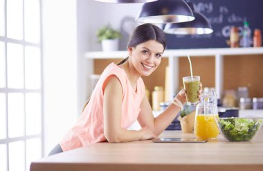 Mutfakta dijital tablet kullanan güzel genç bir kadın..