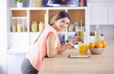 Mutfakta dijital tablet kullanan güzel genç bir kadın..