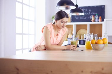 Mutfakta dijital tablet kullanan güzel genç bir kadın..