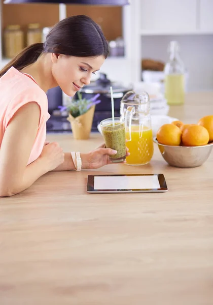Vacker ung kvinna med hjälp av en digital tablett i köket. — Stockfoto
