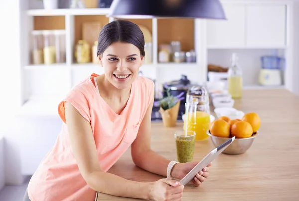 Vacker ung kvinna med hjälp av en digital tablett i köket. — Stockfoto