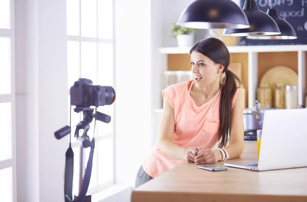 Jonge vrouw in de keuken met laptop computer uitziende recepten, glimlachen. Concept van de voedingsblogger. — Stockfoto