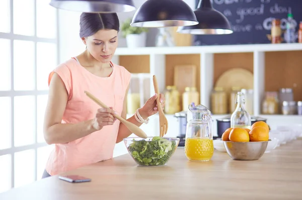 Gülümseyen genç kadın mutfakta taze salata karıştırıyor.. — Stok fotoğraf