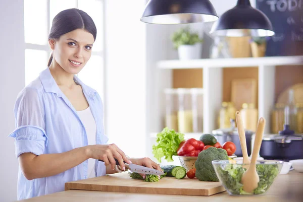 Jeune femme coupant des légumes dans la cuisine à la maison. — Photo