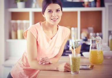 Mutfakta dijital tablet kullanan güzel genç bir kadın..