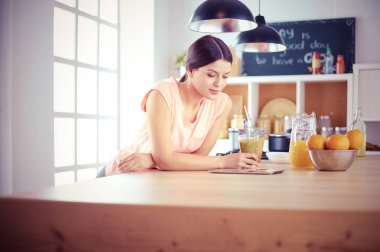 Mutfakta dijital tablet kullanan güzel genç bir kadın..