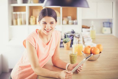 Mutfakta dijital tablet kullanan güzel genç bir kadın..