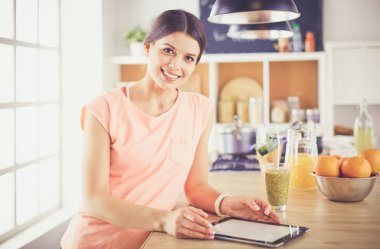 Mutfakta dijital tablet kullanan güzel genç bir kadın..