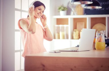 Mutfakta dizüstü bilgisayara benzeyen tariflerle gülümseyen genç bir kadın. Gıda blogcusu kavramı.