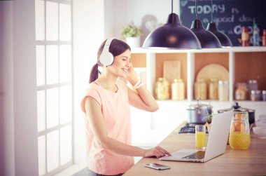 Mutfakta dizüstü bilgisayara benzeyen tariflerle gülümseyen genç bir kadın. Gıda blogcusu kavramı.