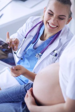 Genç bayan doktor klinikte hamile kadını muayene ediyor..