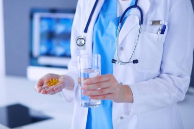 Doktorlar ellerinde haplar ve klinikte bir bardak su tutarken..