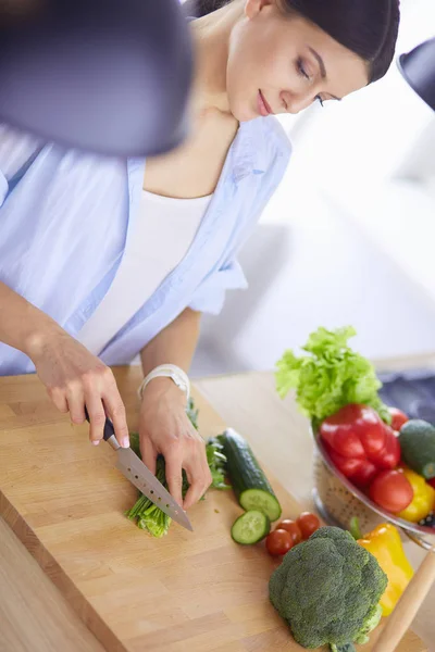 Junge Frau schneidet Gemüse in Küche zu Hause. — Stockfoto