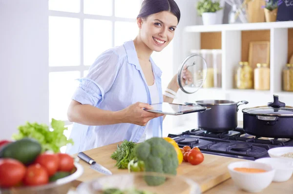 Giovane donna che utilizza un tablet per cucinare nella sua cucina. — Foto Stock