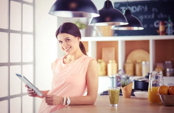 Bela jovem mulher usando um tablet digital na cozinha. — Fotografia de Stock