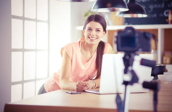 Jonge vrouw in de keuken met laptop computer uitziende recepten, glimlachen. Concept van de voedingsblogger. — Stockfoto