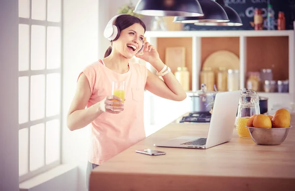 Ung kvinna i köket med bärbar dator ser recept, leende. Begreppet livsmedelsbloggare. — Stockfoto